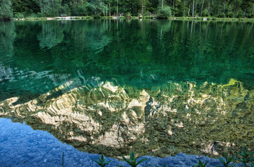 Reflection of mountain and trees in a lake in Bluntautal Valley on a spring evening in Austria.