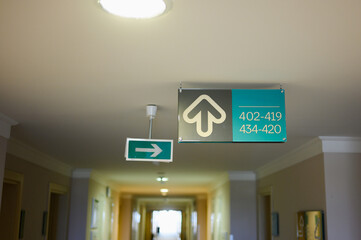 Hotel room sign on hotel ceiling and emergency exit sign. Room numbers, sign in hotel, hostel, apartment. Residential building for living, office rent, hotel room.