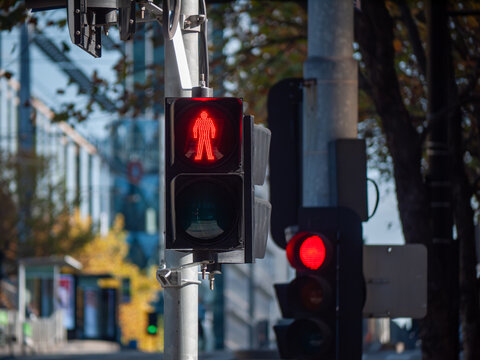 A red pedestrian traffic light signal with a modern LED display showing a red stop symbol—urban infrastructure and road safety systems in Melbourne Australia.