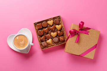 A romantic Valentines Day setup featuring a box of assorted chocolates and a steaming cup of coffee