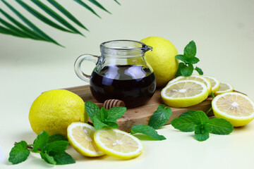 Fresh lemon slices on the chopping board with mint leaves and honey . Herbal drink ingredients with...