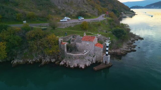 Aerial 4K orbit shot of the historic Gospa od Andjela church and lighthouse in Verige strait, Kotor Bay, Montenegro
