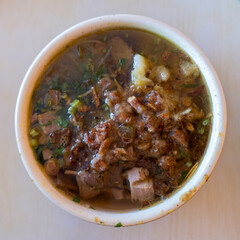 Traditional Indonesian beef soup, as well known as Soto. Indonesian Traditional Meat Soup Bowl with Flavorful Garnishes.