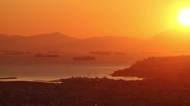 Sunset over Piraeus bay. View from above to industrial cargo ships coming to or departing from Piraeus Port of Athens. Greek cargo transportation by the sea industry. 4k video