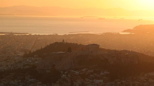 Sunset over Arcopolis hill in Athens. Beautiful orange sky landscape, view from above from Lycabetus Hill, to the Anciend World of Parthenon. Travel to Athens, Greece. 4k video