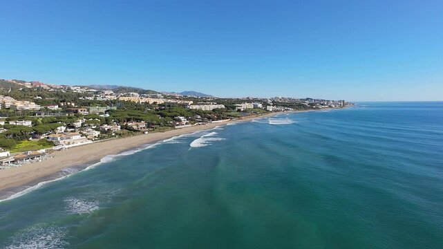 Aerial drone footage of the beautiful beach front in the town of Sitio de Calahonda in Mijas Spain showing the sandy beach and front side apartments from above on a bright sunny day