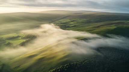Fototapeta premium Morning mist envelops rolling hills in a serene landscape during sunrise