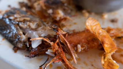 Macro shot of Empty Plate with Leftover Seafood and Sauce Indicating a Finished Meal
