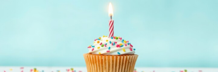 A beautifully styled cupcake with a single lit birthday candle on top surrounded by colorful sprinkles or decorations, food, cupcake, candle