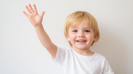 Smiling young boy waves happily in bright indoor setting with simple background.