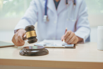 Male doctor working at a desk in a hospital, using a hammer, overseeing legal aspects of healthcare, performing medical duties, managing patient care, ensuring compliance with medical laws,providing