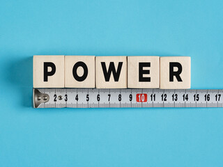 Measuring power: wooden cubes and measuring tape on blue background