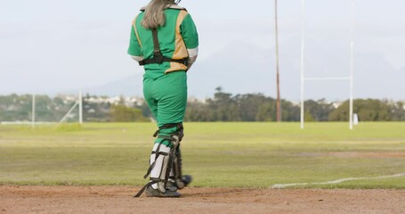 Female baseball player wearing green uniform, catching and throwing the ball on a pitch, copy space - Powered by Adobe