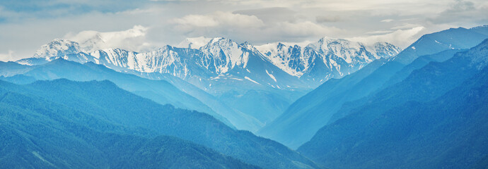 Snow covered mountain peaks in the clouds, panoramic view