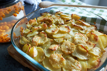 Baked potatoes in a glass baking mould and a kettle of sea buckthorn.