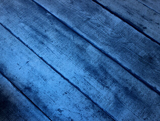 A mystical blue glow is reflected on the old  time damaged wooden boards closeup angle view. Old wooden boards illuminated by strange blue light