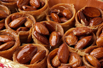 Delicious almond pastries filled with sweet syrup showcased in a traditional container at a market