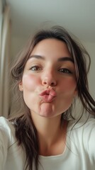 Naklejka premium Young woman making kissy face expression in selfie