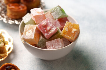 Colorful Turkish delight served in a bowl with assorted sweets on a light blue background