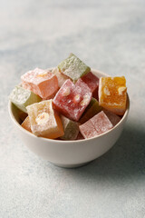 Colorful Turkish delight assortment in a white bowl on a gray background