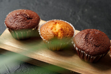 Freshly baked muffins displayed on a wooden board in a cozy setting with soft lighting