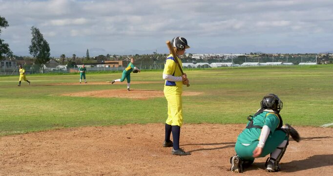 Multiracial female baseball players, catching, throwing and hitting the ball on a pitch