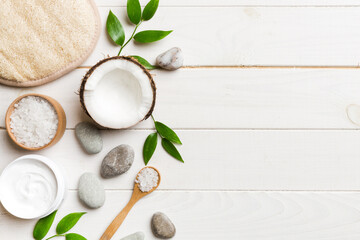 Coconut with jars of coconut oil and cosmetic cream on colored background. Top view. Free space for...