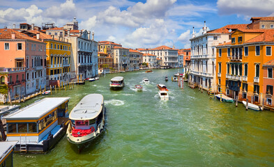 Grand Canal in Venice Italy. Panoramic view to picturesque landscape city with water transport traffic. Motorboats, vaporetto cutters on Sunny summer day blue sky clouds