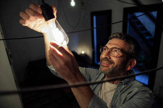 Smiling man changing light bulb at home