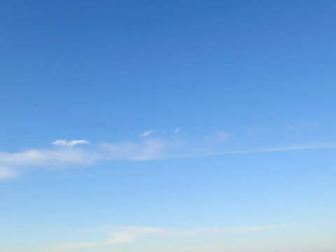 A tranquil blue sky with a few wispy stratus clouds stretching across the horizon, textured, peaceful, stratus clouds