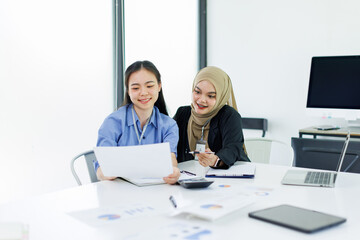 Obraz premium Young businesswoman adviser standing in front of laptop and giving advise to sales woman. Business people consulting at office. asian teamwork concept. 