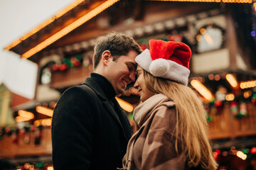 Happy man spending leisure time with girlfriend wearing Santa hat