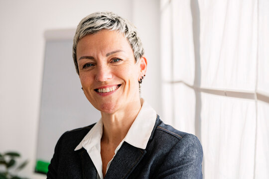 Smiling businesswoman with short highlighted hair in office