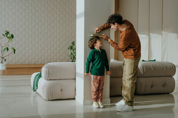 Father measuring son's height at home