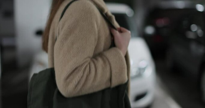 Young woman walks through the parking lot of shopping center to car. Puts paper bags with purchases. Shopping, sale, discounts in stores.