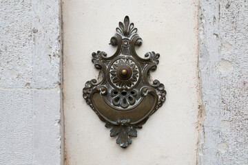 Ornate bronze doorbell mounted on marble surface