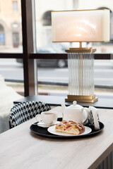 A lush piece of yeast pie with berries in a pastry shop on a table with tea