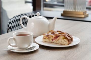 A lush piece of yeast pie with berries in a pastry shop on a table with tea