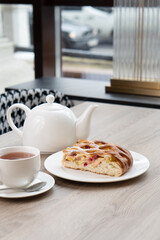A lush piece of yeast pie with berries in a pastry shop on a table with tea
