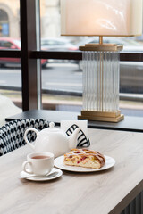 A lush piece of yeast pie with berries in a pastry shop on a table with tea