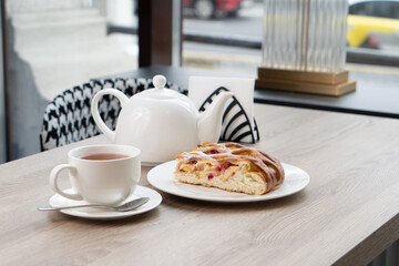 A lush piece of yeast pie with berries in a pastry shop on a table with tea