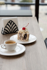 Creamy chocolate cake with and cup of coffee on table in confectionery shop