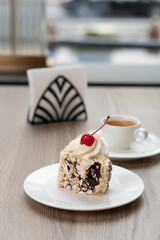 Creamy chocolate cake with and cup of coffee on table in confectionery shop