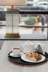 Berry pie piece on plate next to teapot on table in cafe