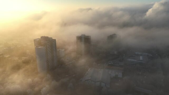 Aerial drone footage of circling around high-rise buildings in the morning mist at sunrise