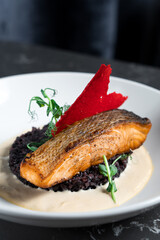 A piece of baked red fish on vegetables in a white bowl