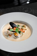 Creamy seafood soup in a white bowl in a restaurant close-up