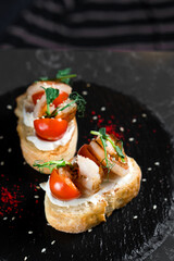 Bruschetta two pieces with shrimps and cherry tomatoes on a black plate