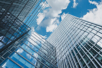 This image captures a dramatic upward perspective of modern glass buildings that reflect the sky, symbolizing the pinnacle of architectural innovation and ambition.