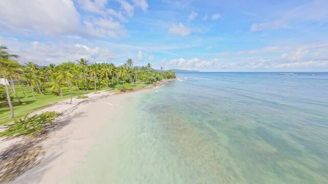 Aerial FPV drone flyover Playa El Aserradero, Dominican Republic, with calm waters and palm trees